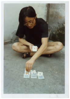 吳山專坐在街上玩牌時攝；另附英文標題「作為街頭表演者，上海，中國，1984」， 1984年攝於上海